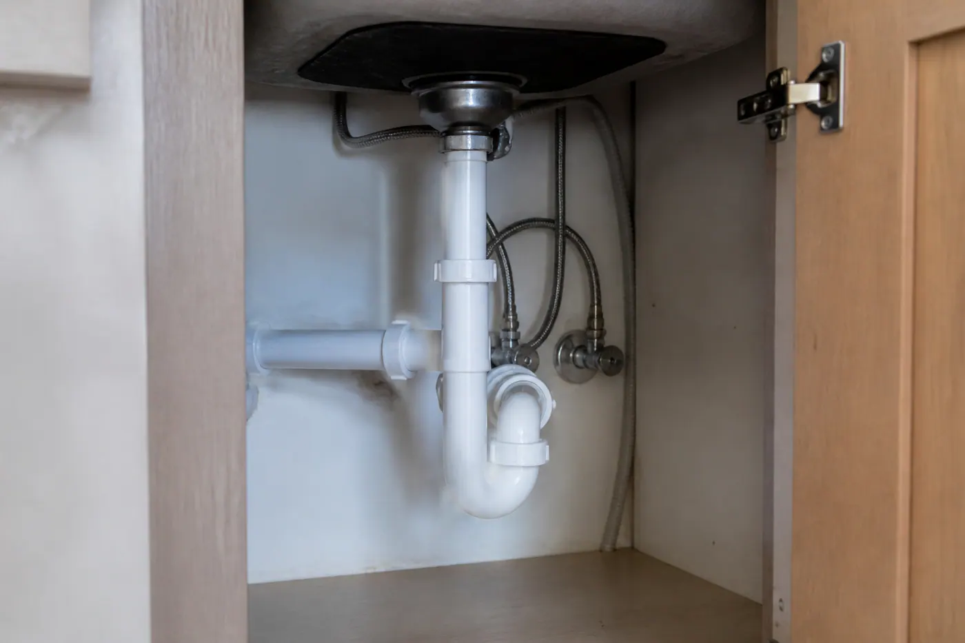 Garbage disposal and drain piping under a kitchen sink
